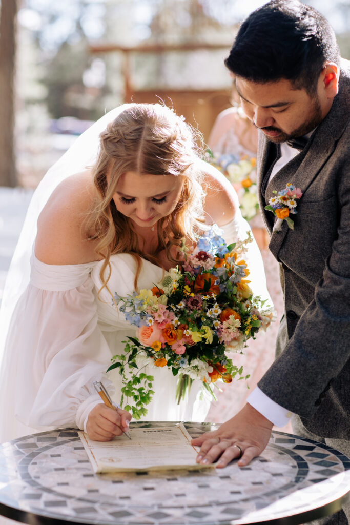 Bride and groom at outdoor wedding signing marriage license